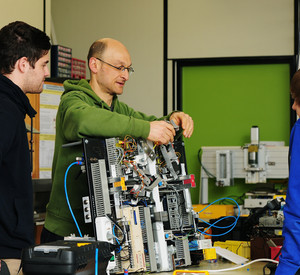 Leher im Gespräch mit zwei Schülern, Elektronik
