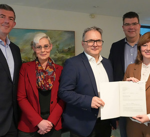 Staatssekretärin Nicole Steingaß überreicht einen Förderbescheid an die Geschäftsführer des Klinikums in Daun