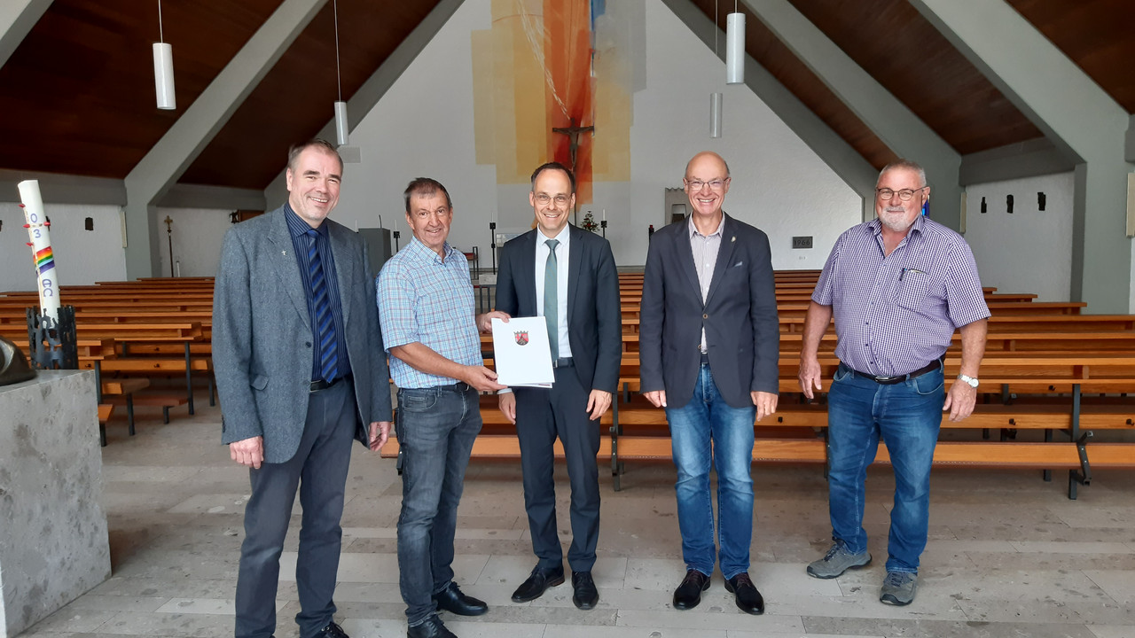 Staatssekretär Denis Alt übergibt Bescheid an Vertreter der Pfarrgemeinde Dümpelfeld in der Pfarrkirche.